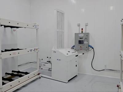 Barrel handler standing in a finished white process room beside its floor-mounted control cabinet, with barrel racks racked to both sides.