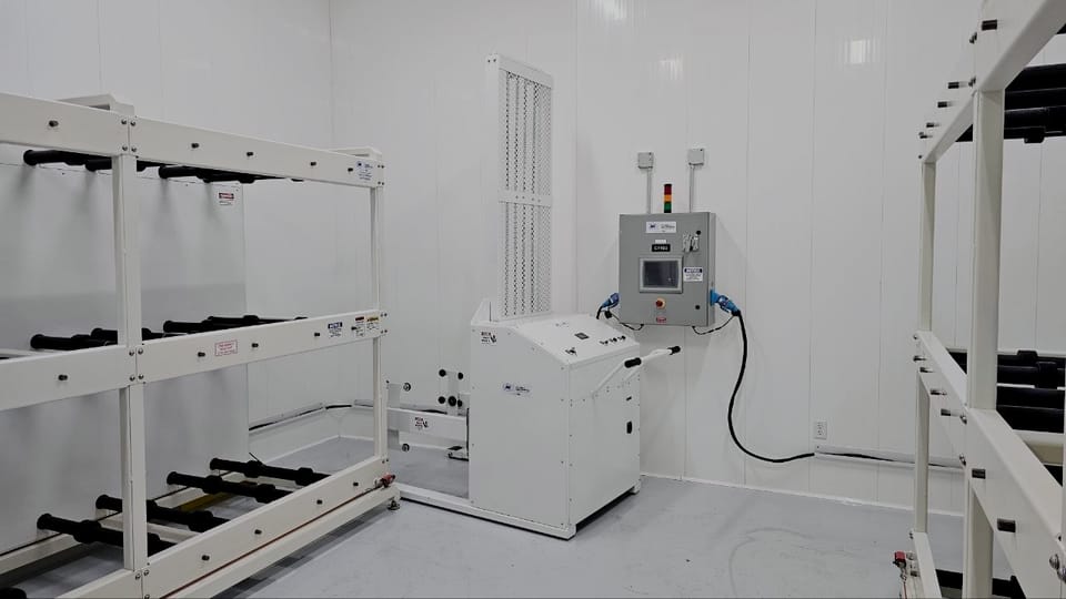 Barrel handler standing in a finished white process room beside its floor-mounted control cabinet, with barrel racks racked to both sides.
