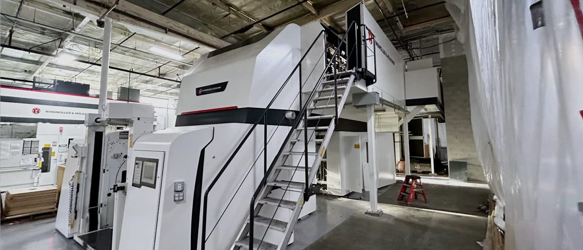 OEM press line set on a plant floor behind temporary containment sheeting, with a fabricated steel access stair and platform on its left flank.